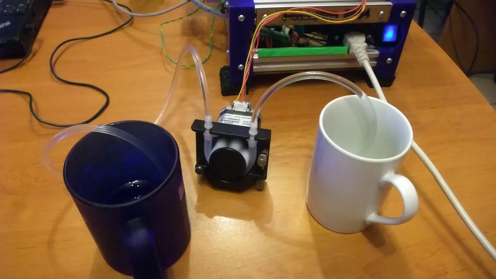 Small peristaltic pump on a bench transferring liquid between two containers