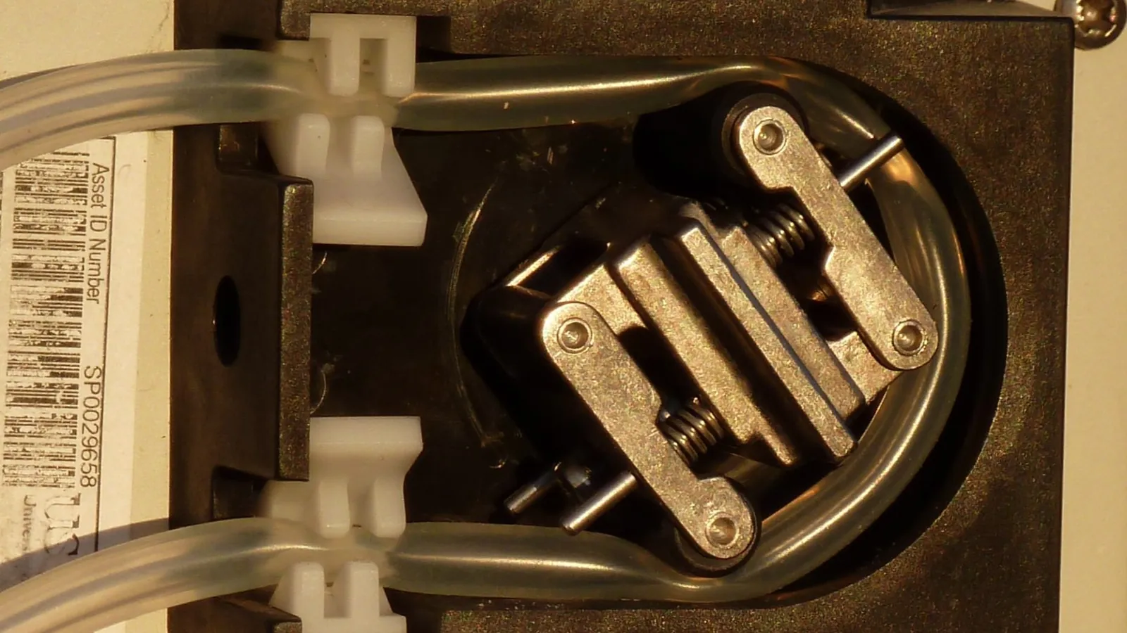 Close-up of a peristaltic pump head squeezing clear tubing