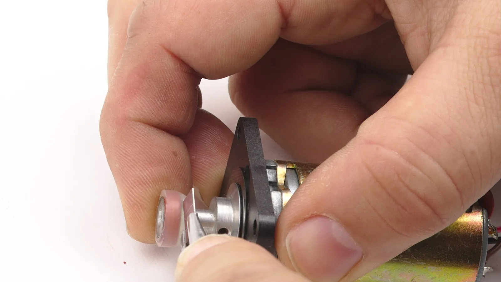 Hands assembling a small peristaltic pump head on a workbench