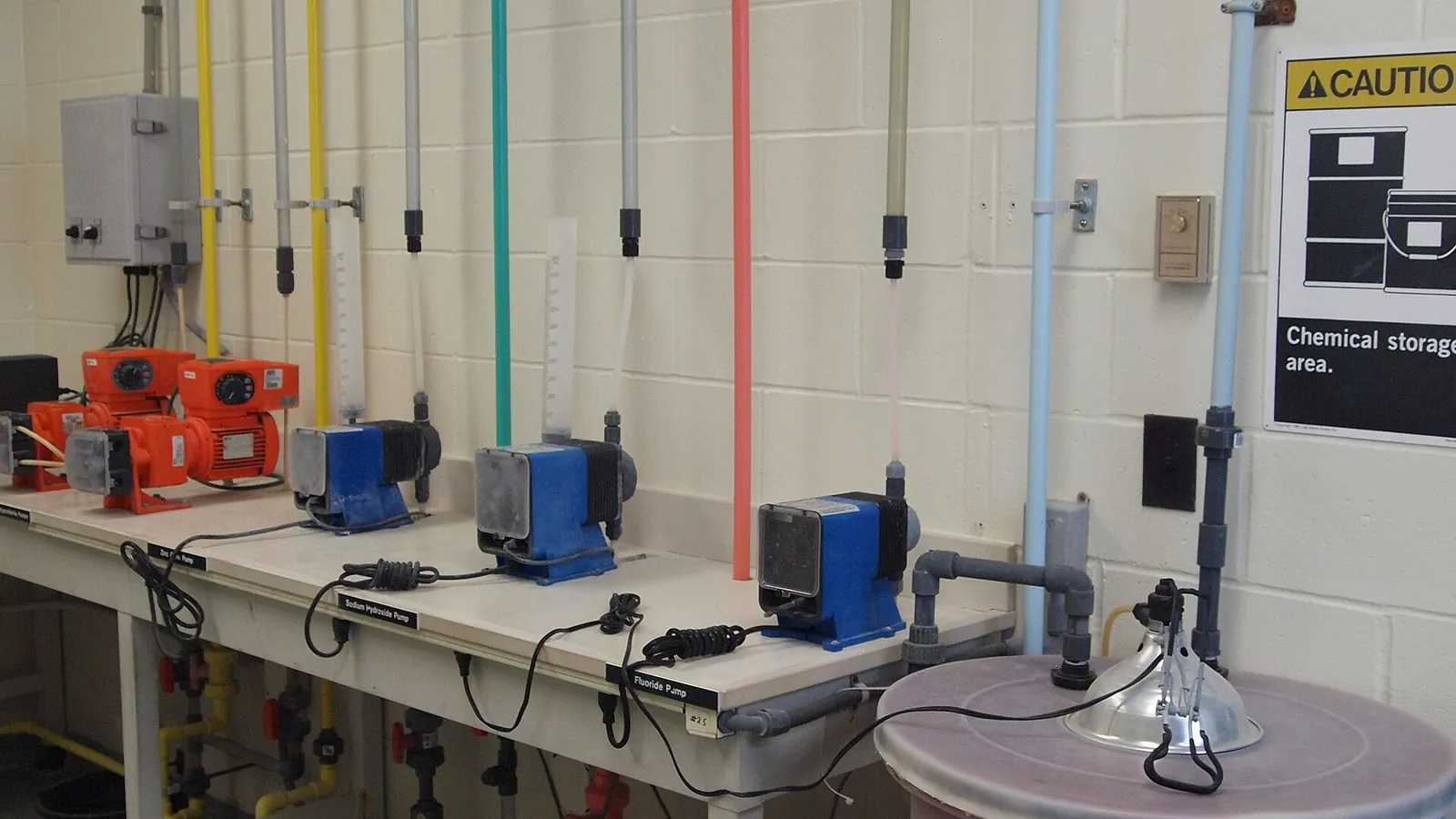Chemical dosing pumps with vertical colored tubing at a water purification plant