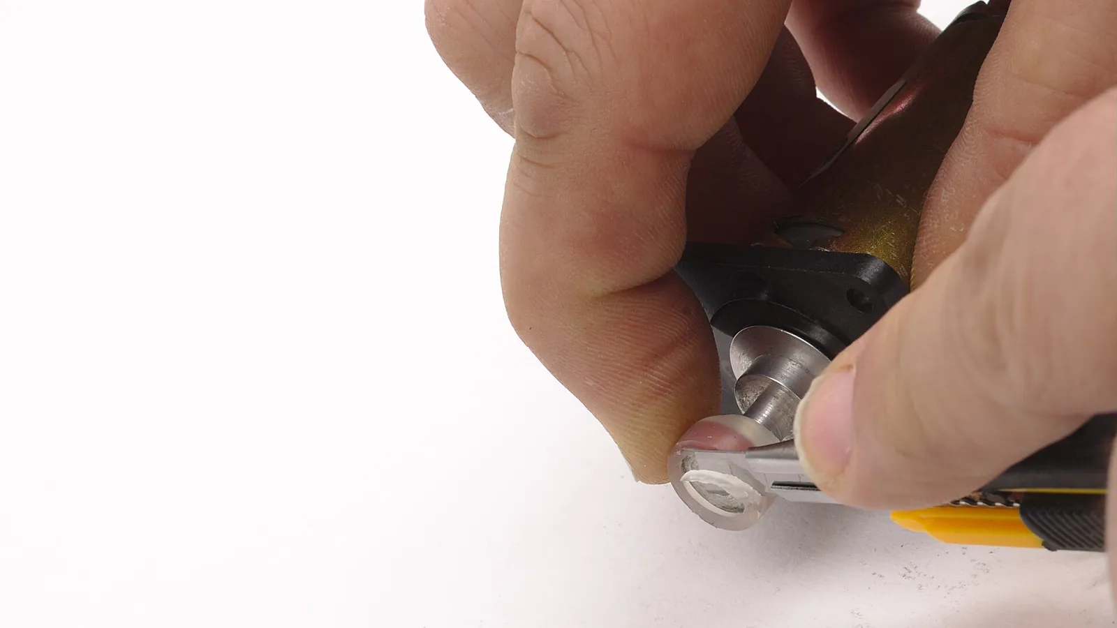 Hands trimming a clear tube on a small peristaltic pump head