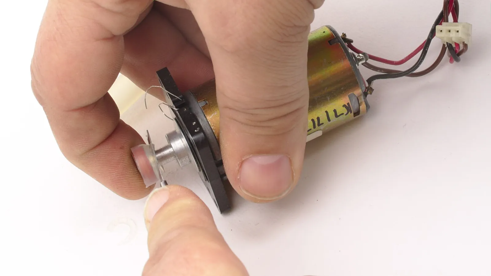 Hands working on a peristaltic pump head with clear tubing