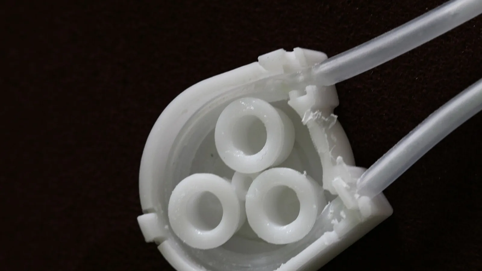 White plastic peristaltic pump head with three rollers and tubing, studio shot